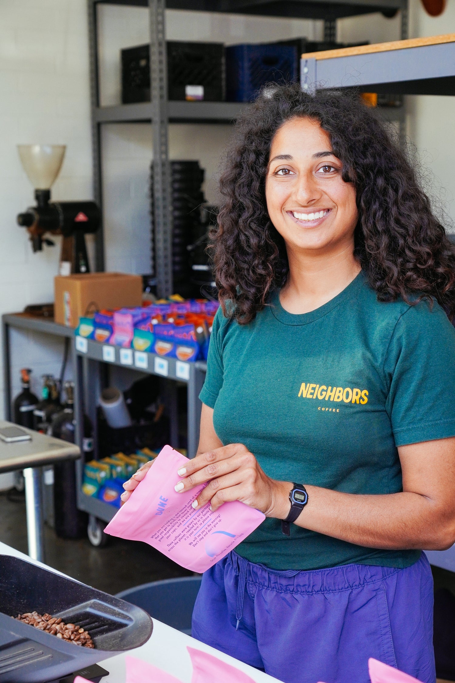 Employee packaging freshly roasted coffee beans into a pink single origin coffee bag