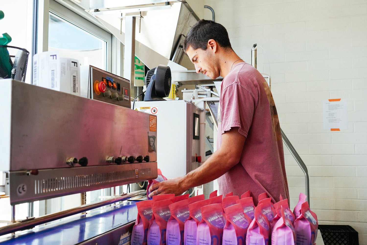 Freshly roasted Pink Single origin coffee bags being sealed for delivery