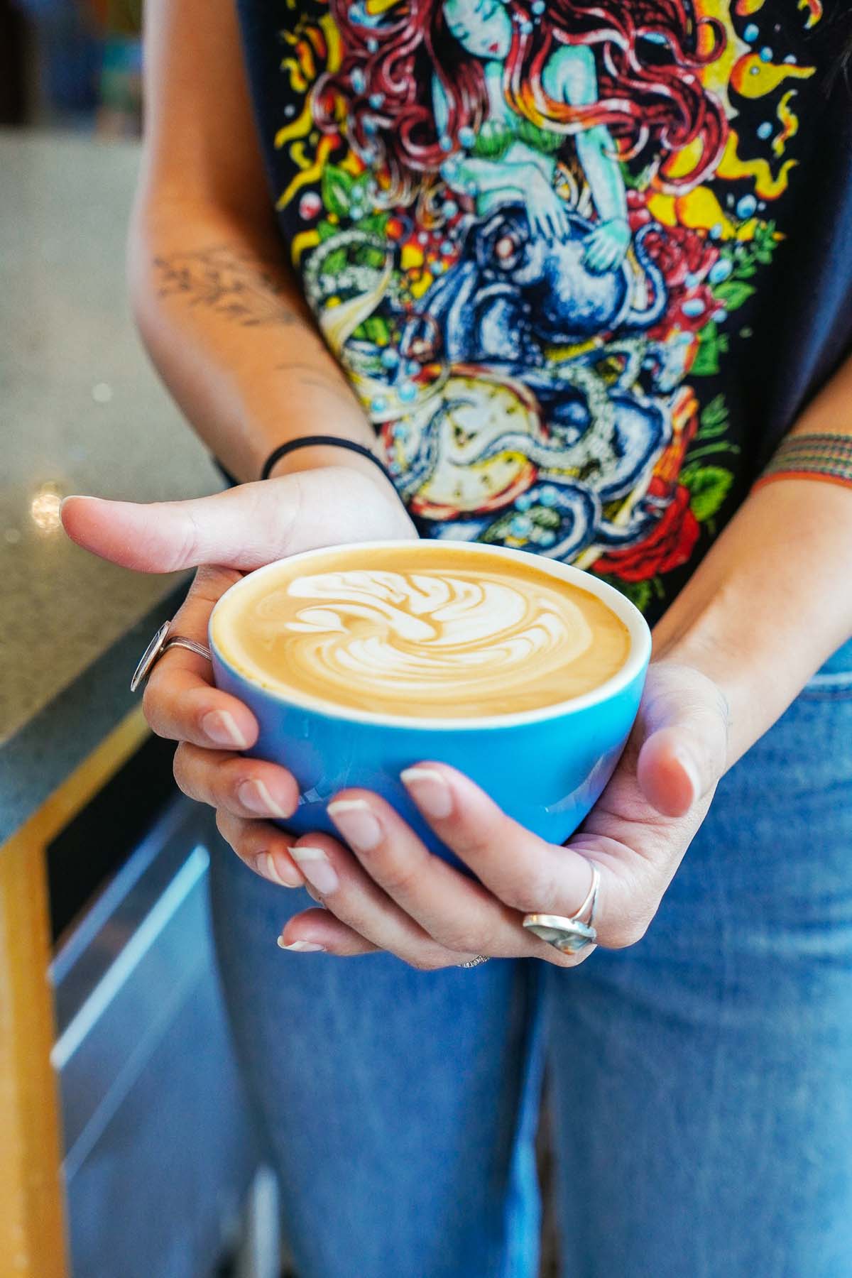 Hand holding large coffee cup with swan latte art